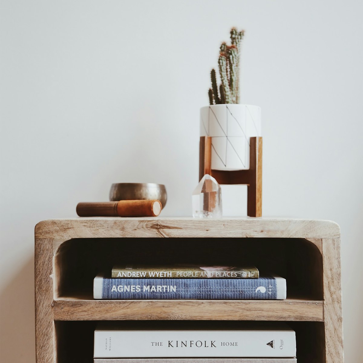 Rounded solid wood bedside table with open shelves holding books